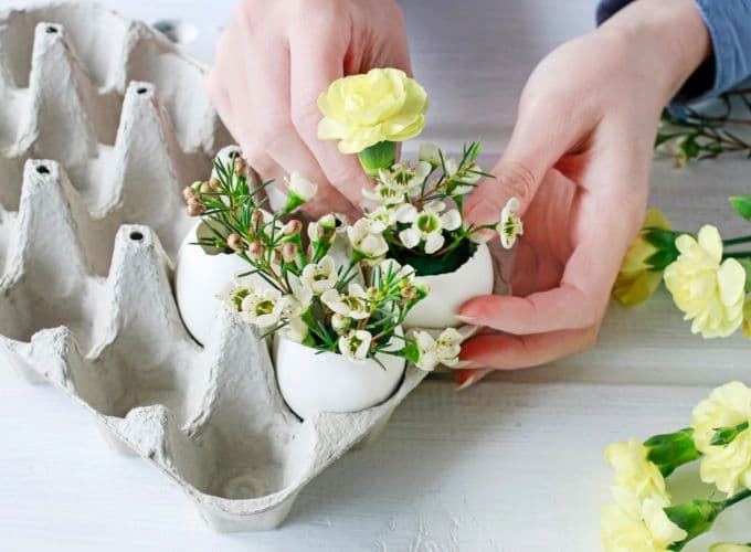 Eierkarton, der mit Eierschalen, Blüten und Zweigen dekoriert wird